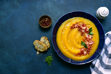 Autumn pumpkin soup with smoked bacon. Top view with copy space.