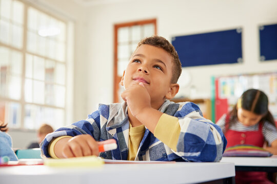 Little school boy thinking in classroom - Powered by Adobe