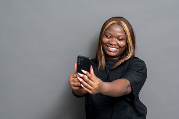 Fototapeta premium excited young black lady holding up her phone