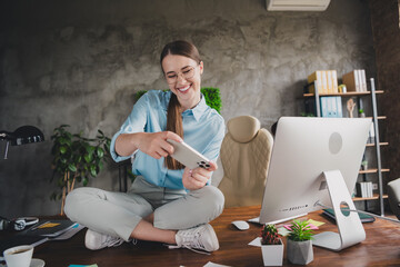 Photo of positive good mood lady specialist dressed shir sitting table playing game modern gadget...