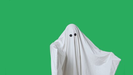 Funny halloween ghost in white sheet isolated on chroma key green screen background shows scary...