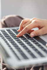 The girl is typing on the laptop keyboard. Girl's hands on the keyboard.