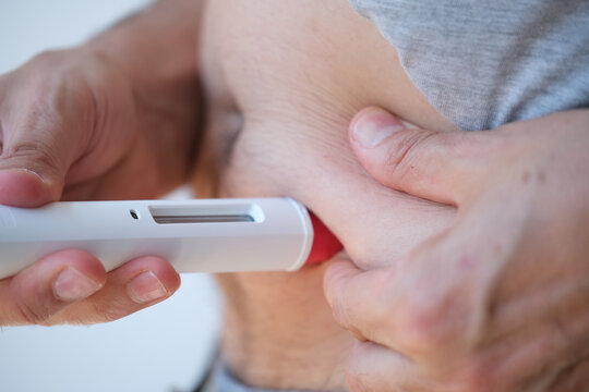 Detail of a man injecting himself in the abdominal area with a biological or insulin type medical treatment. It is a modern injectable healthcare drug such as Adalimumab, Etanercept or epinephrine