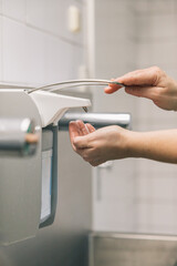 Unrecognizable person taking disinfectant out of the dispenser in a hospital