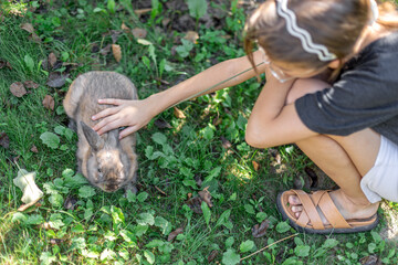 A girl plays with a domestic rabbit on the street. Pet concept.