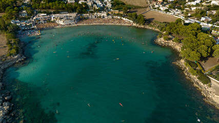 Aerial view of the beach of Lido Gandoli in the municipality of Leporano, near Taranto, in Puglia, Italy. There are many people under the umbrellas and in the sea.