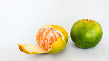 秋冬の果物のイメージ ：緑色がみずみずしい早生の温州ミカン全体と皮をむいた果実