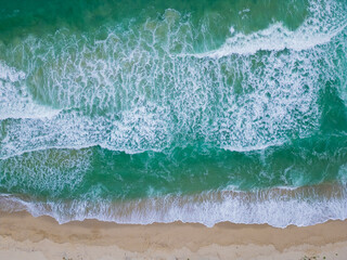 Gentle waves lapping against a sandy beach under bright sunlight in a coastal paradise during midday, creating a serene atmosphere