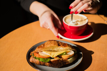 A woman drinks coffee with a croissant in a cafe at a table
