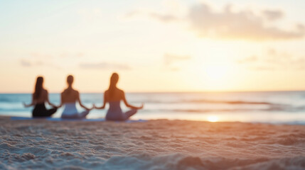 Fototapeta premium Group of people practicing yoga on a beach at sunrise, peaceful atmosphere, wellness, mindfulness, fitness