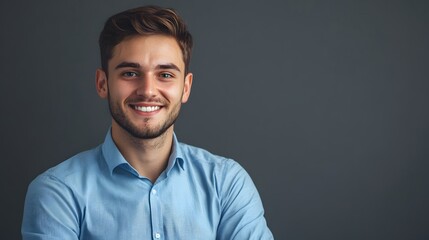 Obraz premium Portrait of a smiling young man in a blue shirt against a gray background