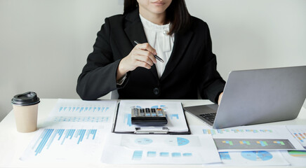 Asian businesswoman sit at their desks and calculate financial graphs showing results about their...