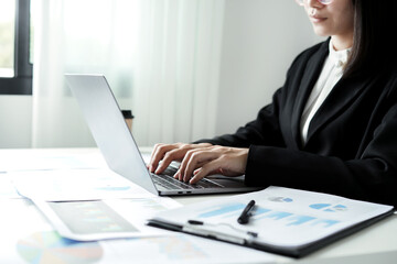 Asian businesswoman sit at their desks and calculate financial graphs showing results about their investments and plan successful business growth process