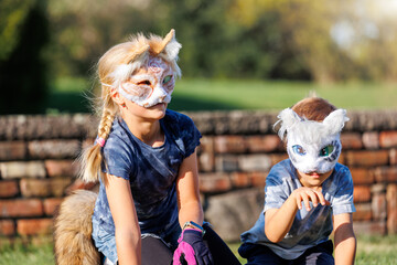 Cute young little kid girl wear cat furry mask enjoy have fun playing outdoors in forest street...