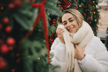 Young beautiful woman enjoying Christmas decorations on city street.