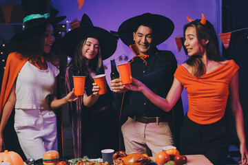 Joyful office Halloween party with coworkers in costumes, celebrating with drinks and laughter, fostering teamwork and festive spirit