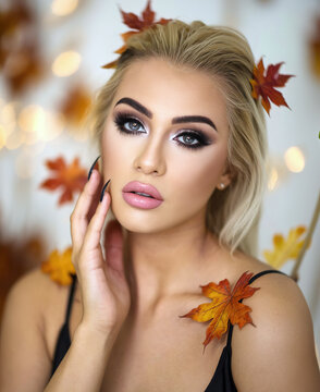 Herbstliches Foto einer sch&ouml;nen blonden Frau mit perfektem Permanent Make-Up und Gel-Fingern&auml;geln mit herbstlicher Deko