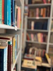 A close-up view of colourful books on a library shelf, with blurred shelves in the background, evoking the timeless charm of a cosy reading space.