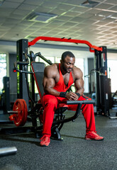 Muscular man training in a gym wearing red attire.