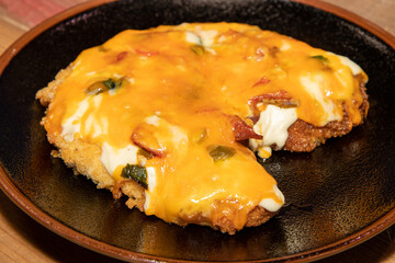 A delicious plate of Chicken Parmo on a plate on a wooden kitchen table