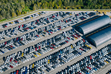 Aerial drone view of Parking lot. New cars storage area. Many cars parked in a rows