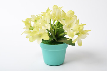 Beautiful artificial green plant yellow flowers in green pot isolated on white background. House plant