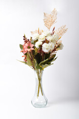 Beautiful artificial flower bouquet in glass vase isolated on white background