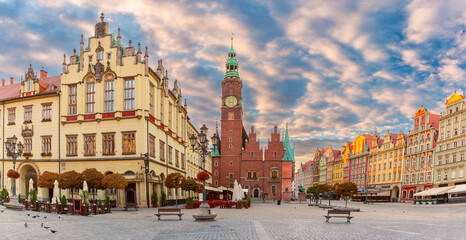 Obraz premium Morning view of colorful buildings on Rynek Square in Wroclaw, Poland, with street lamps and a partly cloudy sky