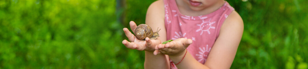 Child holding a snail on his hand. Selective focus.
