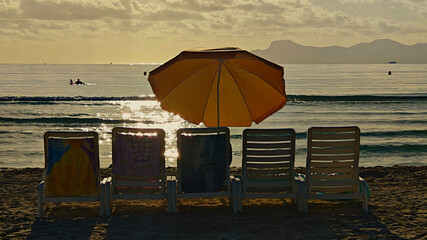 Five sun loungers in a row and a parasol on the beach