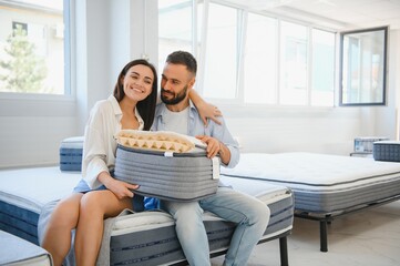 A married couple chooses a new bed for the bedroom and an orthopedic mattress in a furniture store