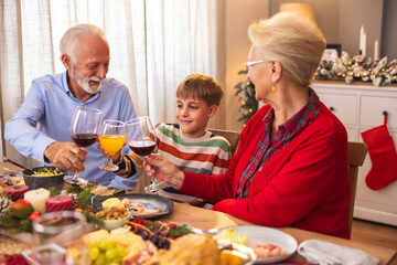 Boy making a toast with grandparents while having family Christmas dinner
