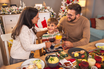 Parents making a toast with son while having family Christmas dinner