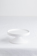 Empty tableware - white plate cakestand on white table as a background for a dessert vertical photo with a copy space, food mokup