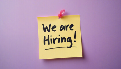 Yellow sticky note on purple wall announcing we are hiring