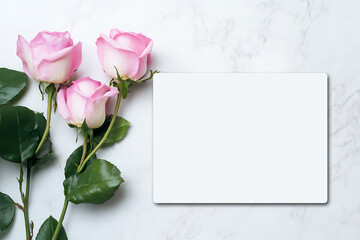 A blank white postcard, a few pink roses on the left side of it, a light gray marble texture background