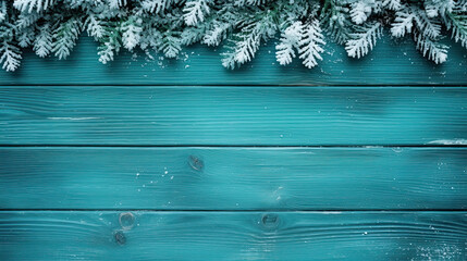 Fototapeta premium Snowy spruce branches on a teal wood background