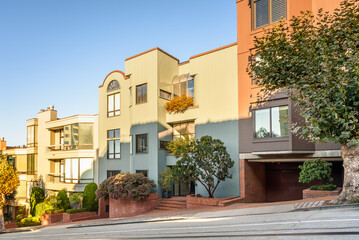 Modern apartment buildings along a steep street in San Francisco on a clear autumn day