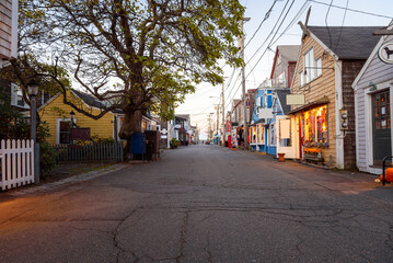 Old wooden buildings with colourful shops and restaurants line a pedestrian street in a fishing village at dusk in autumn