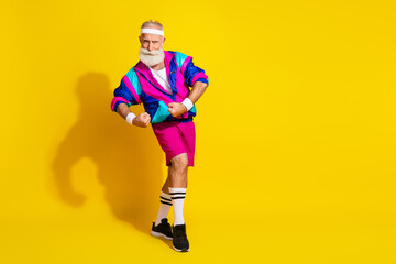 Full length photo of handsome good mood senior guy oldschool sportswear showing biceps emtpy space isolated yellow color background