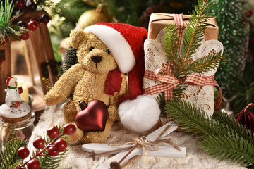 Christmas arrangement with teddy bear in Santa hat sitting next to a gift box