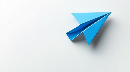 Naklejka premium A blue paper airplane sits on a white surface.