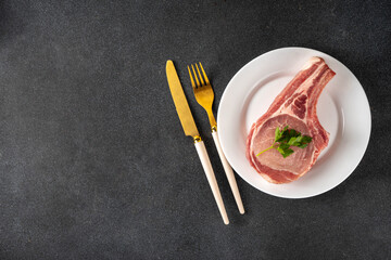 Raw meat diet, Raw Carnivore Animal-based Diet. Plate with tasty spiced meat steak, with cutlery, ready for eating, copy space