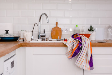Clutter, dirty dishes by the sink in the white kitchen
