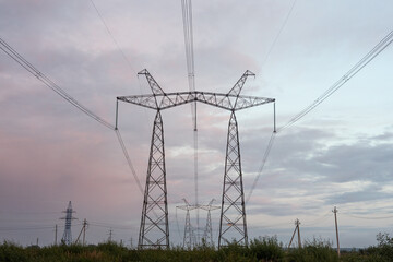High voltage pylons against the dramatic cloudy sky. Power lines stretching into the distance....