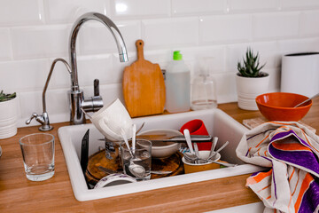 Clutter, dirty dishes by the sink in the white kitchen