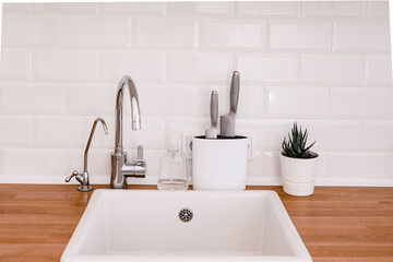 Clean white sink on wooden table in white kitchen