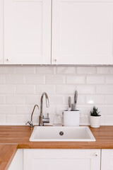 Clean white sink on wooden table in white kitchen