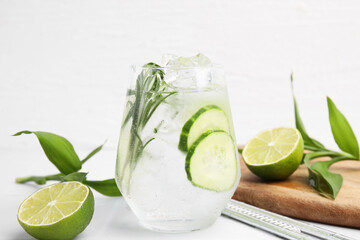 Refreshing water with cucumber and rosemary in glass on white table