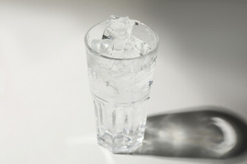 Refreshing water with ice in glass on grey background, closeup